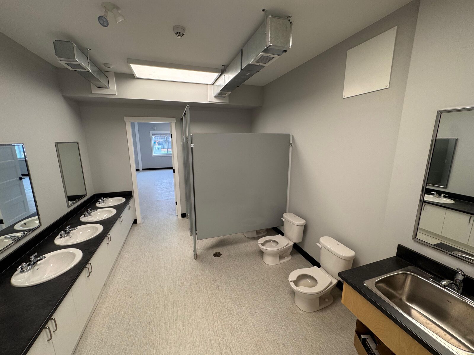 Children's washroom with row of sinks, mirrors and child-height toilets