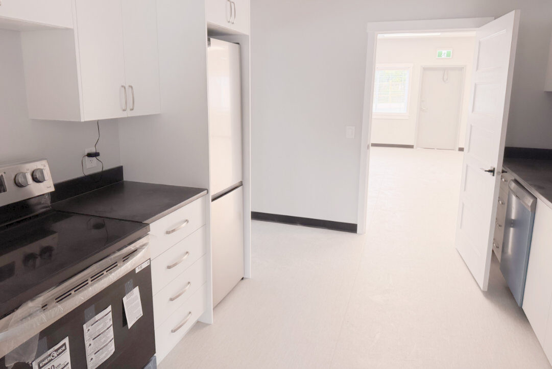 Kitchen with electric range, fridge and hallway view