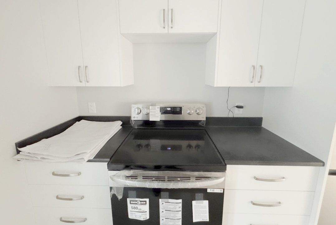 Kitchen with range, white cabinets and dark counter