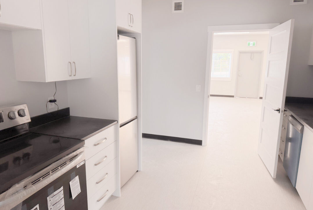 Kitchen counters with range, fridge and hallway